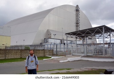 CHERNOBYL UKRAINE 09 03 17: Man in front the Nuclear Power Plant sarcophagus is a massive steel and concrete structure covering the nuclear reactor No. 4 building of the Chernobyl Nuclear Power Plant