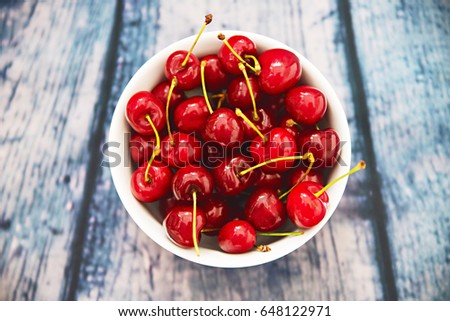 Cherries in bowl on wooden table 
