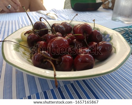 Cherries in a white bowl with fruit drwaing and quite mature or ripe