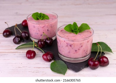 Cherry Banana Smoothie In Low Glasses On A Black Slate Board.
