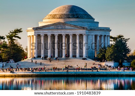 Cherry blossoms tree during spring time lined up in Washington DC's river bank. The Thomas Jefferson Memorial on the background.