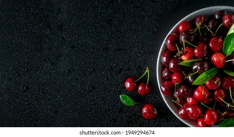 Cherry In A Bowl On A Black Background With Water Drops, Copy Space.