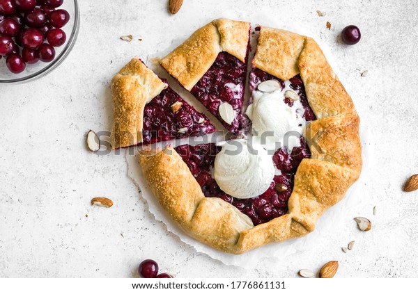 Cherry Galette with almonds and vanilla ice\
cream on white, top view, copy space. Homemade healthy dessert -\
cherry pie or french\
galette.