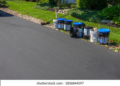 Cherry Hill, New Jersey- August, 2020: A Row Of Nine Buckets Containing Tar Used To Coat An Asphalt Driveway Are Seen On A Path Of Stones At The Side Of The Driveway