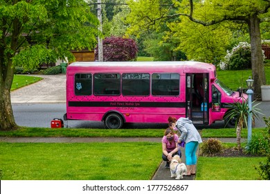 Cherry Hill, New Jersey - July, 2020: A Pink School Bus Used As A Dog Grooming Spa Parked On A Street In Front Of A House With The Groomer Talking To The Dog Owner