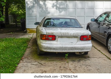 Cherry Hill, New Jersey - July, 2020: Rear view of an extremely dirty white car in a driveway in front of a white garage door
