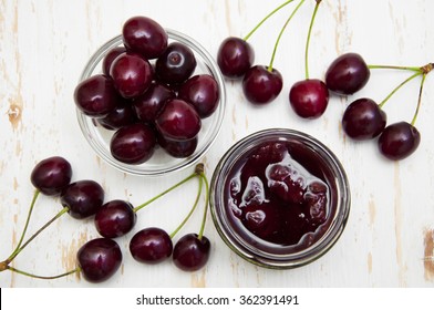 Cherry jam with fresh cherries on a wooden background
