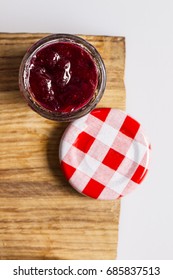 Cherry Jam In Mini Jar And Checked Lid On A Wooden Board, Top View