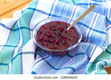 Cherry jam in a saucepan of rich color on a wooden spoon..