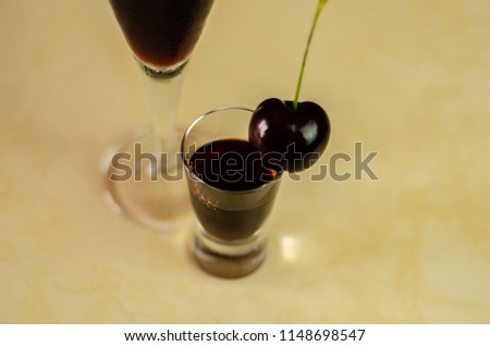 Cherry liqueur and juicy ripe cherries on the table in  the bar, an elegant serving of sweet drink in the restaurant, a traditional drink