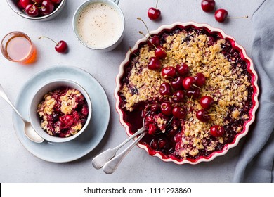 Cherry, red berry crumble in baking dish. Grey stone background. Close up. Top view.