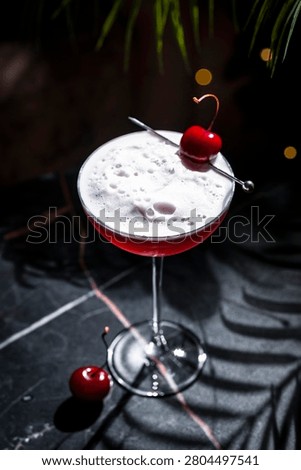 Cherry Sour cocktail high angle view. Close up shot focusing on thick white egg white foam and cocktail pick.