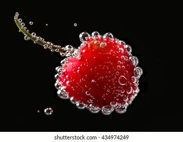 Cherry In Sparkling Water On Black Background.