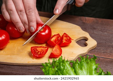 Cherry tomato is cut with a knife on a wooden board on the table. Horizontal photo. - Powered by Shutterstock