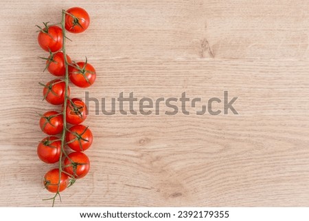 Cherry tomato sprig on wooden background, healthy food concept.