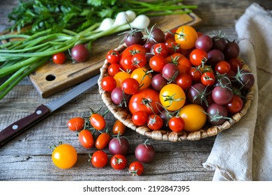 Cherry tomatoes are in the basket on a rough wooden table. Vegetables for salad preparation. - Powered by Shutterstock
