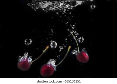 Cherry, Water Splash, Air Bubbles On A Black Background.
