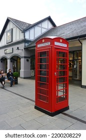 Cheshire Oaks, UK - July 20, 2017: Red Phone Booth With Store Background