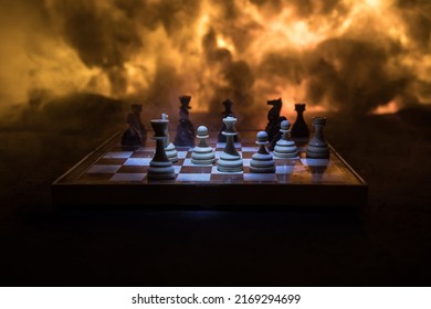 Chess Board Game Concept Of Business Ideas And Competition Or War Theme. Chess Figures On A Dark Background Of Explosion And Fire Clouds. Selective Focus