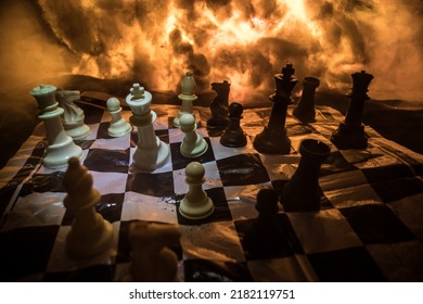 Chess Board Game Concept Of Business Ideas And Competition Or War Theme. Chess Figures On A Dark Background Of Explosion And Fire Clouds. Selective Focus