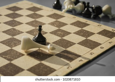 A Chess Field And Black And White Figures. The Pawn Beat The King. The Outcome Of The Game, An Unexpected Denouement. Muted Tones, Macro Shooting.