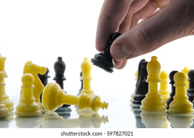 Chess Game, Black Pawn Makes A Move. Pieces On The Board. Man Plays Chess And Makes Smart Move Pawn. Chessman Playing Chess On A White Background, You Can See His Hand.