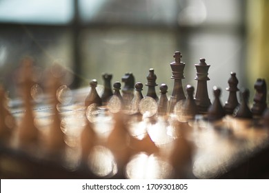 
Chess game with black and white wooden chips on wooden board. At sunset. Realistic.