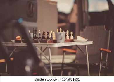 Chess Game On A Camping Table Next To Camper Van. No People.