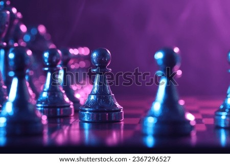 Chess pawn on checkerboard in color light, selective focus