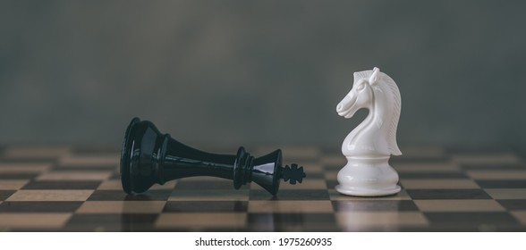 Chess Pieces on Board for Game and Strategy concept. White Chess Knight among lying down black king on chessboard.