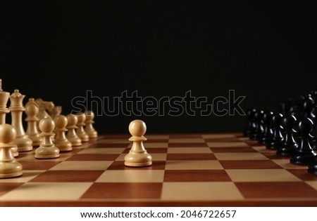 Chess pieces on wooden board against black background