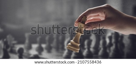 Chess player holding a piece and chess game on the chessboard in the background, game tournament concept