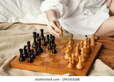 Chess Player Woman Learns Chess Opening By Playing With Himself. White Pawn One Step Forward. Chess Wooden Board With Chess Pieces On Light Background. Strategy Board Game Played. Closeup Toned Photo