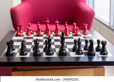 Chess Set On A Table With Red Chair Background