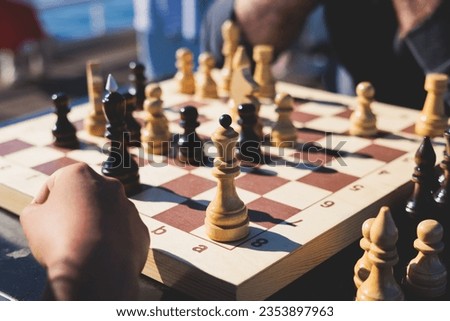 Chess tournament, kids and adults participate in chess match game outdoors in a summer sunny day, players of all ages play, competition in chess school club with chessboards on a table