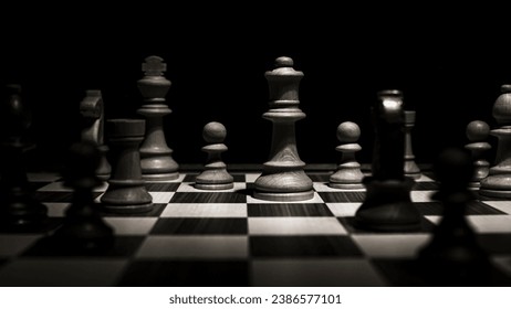 Chessboard with various pieces fighting during a game. Low-key concept picture taken in studio and concerning decision making and strategy.