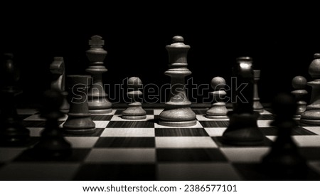 Chessboard with various pieces fighting during a game. Low-key concept picture taken in studio and concerning decision making and strategy.
