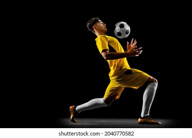 Chest the ball. Young male football player in yellow uniform training isolated on black background. Concept of action, team sport game, energy, vitality. Copy space for ad. - Powered by Shutterstock