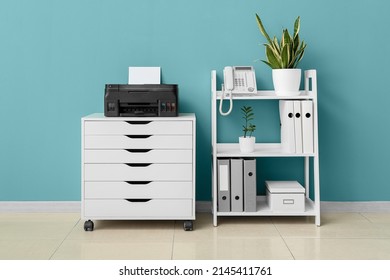 Chest of drawers with modern printer and shelf unit near color wall in room interior