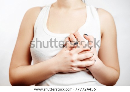 chest pain, girl in a white T-shirt holds her hands to her chest, close-up
