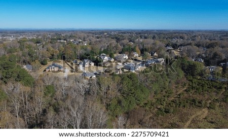 Chestnut Mountain and high voltage power lines over low density residential neighborhood in lush green forest area Flowery Branch, Georgia, USA. Aerial view suburban two-story single-family homes