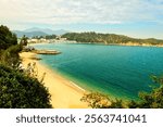 Cheung Chau, Hong Kong - December 18 2024: Cheung Chau island beach and buildings in Hong Kong (Dumbbell island). With the Lantau mountain in the background in the morning in Hong Kong in winter.