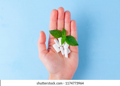 Chewing Gum With A Piece Of Fresh Mint In A Hand On A Blue Background. Fresh Breath, Mint Chewing Gum