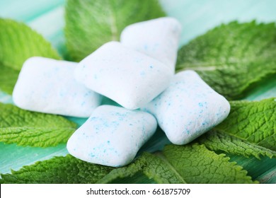 Chewing gums with mint leafs on wooden table