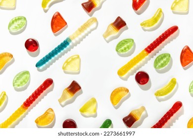 Chewing marmalade of different shapes, tastes and colors lie in a pattern on a white background.  Free space in the center