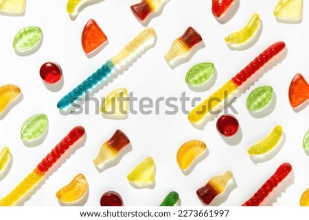 Chewing marmalade of different shapes, tastes and colors lie in a pattern on a white background.  Free space in the center