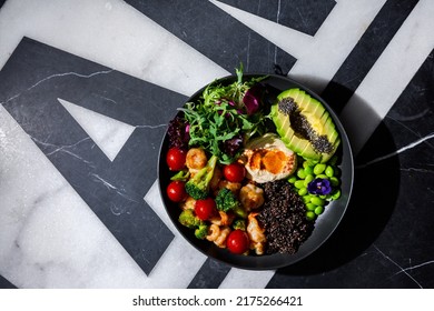 Chia Salad With Tomatoes, Shrimps, Broccoli, Arugula, Sesame Seeds, Endive, Mashed Potatoes, Avocado, Beans, Violet Flower In A Plate On A Background With A Letter