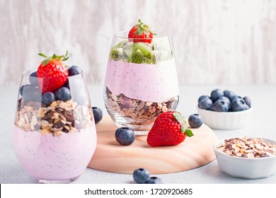 Chia seeds pudding with granola, blueberry and strawberry in glasses. Yogurt with chia seeds, berries, kiwi and muesli for healthy breakfast, copy space - Powered by Shutterstock