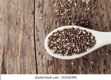 Chia Seeds In White Spoon On Wooden Table