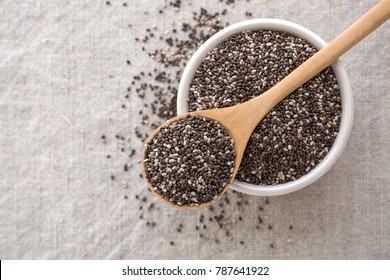 Chia seeds in wooden spoon and bowl from top view with space